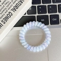 Close-up of spiral phone cord hair tie with blue and purple floral patterns on a desk - Four-Leaf Clover