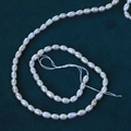Strang mit 4mm weißen ovalen Süßwasserperlen auf grünem Samt für DIY-Schmuck - 4-4,5 mm / 39-40 cm Strang / Natürliches Weiß