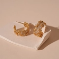 Detailed view of gold C-shaped earrings with micro-paved zircons on white stone base - Zirconia C-Shape Studs / Gold
