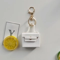 Close-up of white mini PU leather bag keychain with golden metal clasp and ring detail - White
