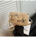 Detalle de bolso en cuero mate beige con hebilla plateada vintage y cierres decorativos - Blanco