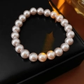 Gros plan des perles de bracelet blanc-rose sur une boîte à bijoux noire sous lumière - Style de Perles Roses 8mm