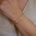 Detailed view of layered 18K gold plated snake and bead chains on woman's wrist - Snake And Bead Layered Style (Style 01)