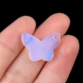 Purple and blue gradient crystal butterfly pendant shown held in hand on black background - Opal (Synthetic)