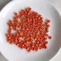 Nahaufnahme leuchtend oranger Acryl-Röhrenperlen auf einem weißen Keramikteller für DIY - 9# Orange
