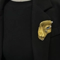 Detailed view of a gold half-face mask brooch with a blue eye on a black suit lapel - Gold Brooch