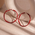 Macro shot of bright red wavy twisted hoop earrings with glossy finish on a ceramic stand - 4.8cm / Red