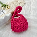 Pink chunky knit handmade handbag with a twist handle shown in a lifestyle setting - Rose Red