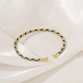 Detailed view of the three-color braided metallic bracelet with gold-tone round end caps - Multicolor (Gold/Silver/Black)