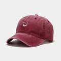 Close-up of wine red washed cotton baseball cap featuring a white embroidered smiley face - Adjustable / Burgundy