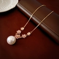 Macro shot of faux pearl pendant with five pink zircon flowers on golden necklace - Pink Flower Pearl Necklace
