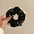 Elegant black and white silk scrunchie with delicate pearl embellishments in hand - Black