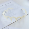 Chic milky white wavy plastic headband with teeth for grip shown on a magazine background - Cream White (Wave Matte)