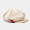 Dettaglio del cappello newsboy beige con trama tessile e bottoni colorati - Taglia unica / Beige