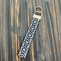 Dettaglio del portachiavi intrecciato a mano bianco e nero su legno stile vintage - Geometrico Nero Bianco