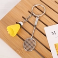 Dettaglio di un portachiavi con racchetta da badminton argento e volano giallo su legno - Racchetta Con Chiusura / Giallo