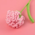 Macro detail of a hand-knitted pink carnation with green leaves on pink background - Carnation / Korean Pink