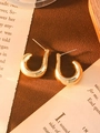 Close-up of gold-plated U-shaped earrings on a vintage newspaper background - Gold Medium C-Shape