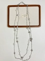 Flat lay of a long silver pearl necklace with diverse heart and clover charms on a tray - Silver Imitation Pearl Heart Clover Multi-Pendant Necklace