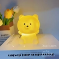 Cute yellow bear night light with soft warm glow on a decorative book surface - White Bear