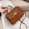 Brown quilted crossbody bag with gold lock and top handle held by hand - Brown