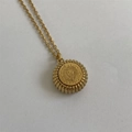 Gros plan du collier doré avec pendentif médaillon tête de lion et bordure côtelée - Lion