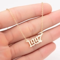 Detail of hand holding a 1997 gold stainless steel necklace with a gothic number pendant - 1997 / Gold