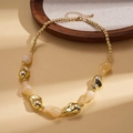 Dettaglio di perle dorate irregolari e perle acriliche bianco panna sulla collana - Bianco