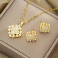 Elegant gold clover jewelry set with white pearls and sparkling zircons on a beige box - Necklace and Earrings Set