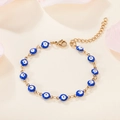Detail van 18K vergulde armband met blauwe emaille boze oog bedeltjes op bloemige achtergrond - Donkerblauw