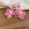 Nahaufnahme von rosa Bast- und Chiffon-Blumenohrringen auf rustikalem Holzhintergrund. - Stil 44 / Rosa