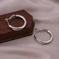 Elegant polished silver twisted hoop earrings displayed on a premium wood and silk stand - E-064---Platinum