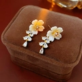 Close-up of elegant flower earrings with shell petals and teardrop zircon tassels - Gold