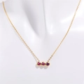 Primer plano de collar chapado en oro con tres circonitas rosas sobre un maniquí - Octubre