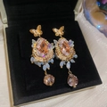 Detalle de pendientes vintage de mariposa de cristal sobre un joyero de terciopelo negro - Poste de plata - Dorado - Rosa
