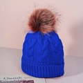 Detail of royal blue cable knit winter hat with large brown faux fur pompom and ribbed cuff - One Size / Sapphire Blue
