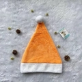Flat lay of an orange plush Christmas hat with pine cones and golden bells decoration - Orange Plush Hat