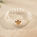 Detail of clear crystal beaded bracelet with a gold clover charm on stone surface - White Crystal Clover (Includes Exquisite Gift Box) / 6mm Bead Diameter