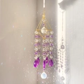 Golden suncatcher with K9 crystal prisms casting rainbow light on a white wall - Purple