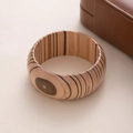 Primo piano di un ampio bracciale in legno con trama naturale marrone chiaro su sfondo morbido - L411 Caffè Chiaro