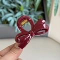 Detail shot of a wine red bow hair claw clip made of glossy resin with a gold metal spring - Ancorra Red - Small Bowknot