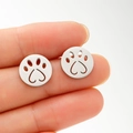 Close-up of silver cat paw stud earrings with heart cutouts held to show size - Steel
