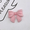 Dettaglio macro del fiocco rosa confetto con bordi decorati da piccole perle bianche - Rosa
