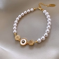 Detailed view of pearl bracelet with golden evil eye and sunburst charms on silk - 6# Bracelet-Gold-Pink-Gold Plated