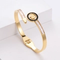 Elegante bracciale dorato con quadrifoglio, pietre baguette e bordo di diamanti neri - Oro