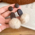 Detalle de pendientes ovalados de madera con pompón de piel beige en ambiente cálido - Estilo Ovalado (Pin de Plata-Marrón)