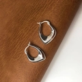 Macro view of S925 sterling silver hoop earring detailing mirror polish on leather - Irregular Geometric Hoop / Silver
