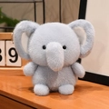 Plush elephant doll in soft grey-blue faux fur displayed on a warm wooden tabletop - Blue Elephant / 15CM