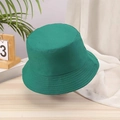 Detail shot of a dark green cotton bucket hat on a wooden desk with decorative greens - One Size / Green