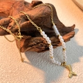 Goldene Meerjungfrauenschwanz Kette mit weißen Perlen auf rustikalem Holzhintergrund - Fischschwanz-Anhänger / Gold/Weiß